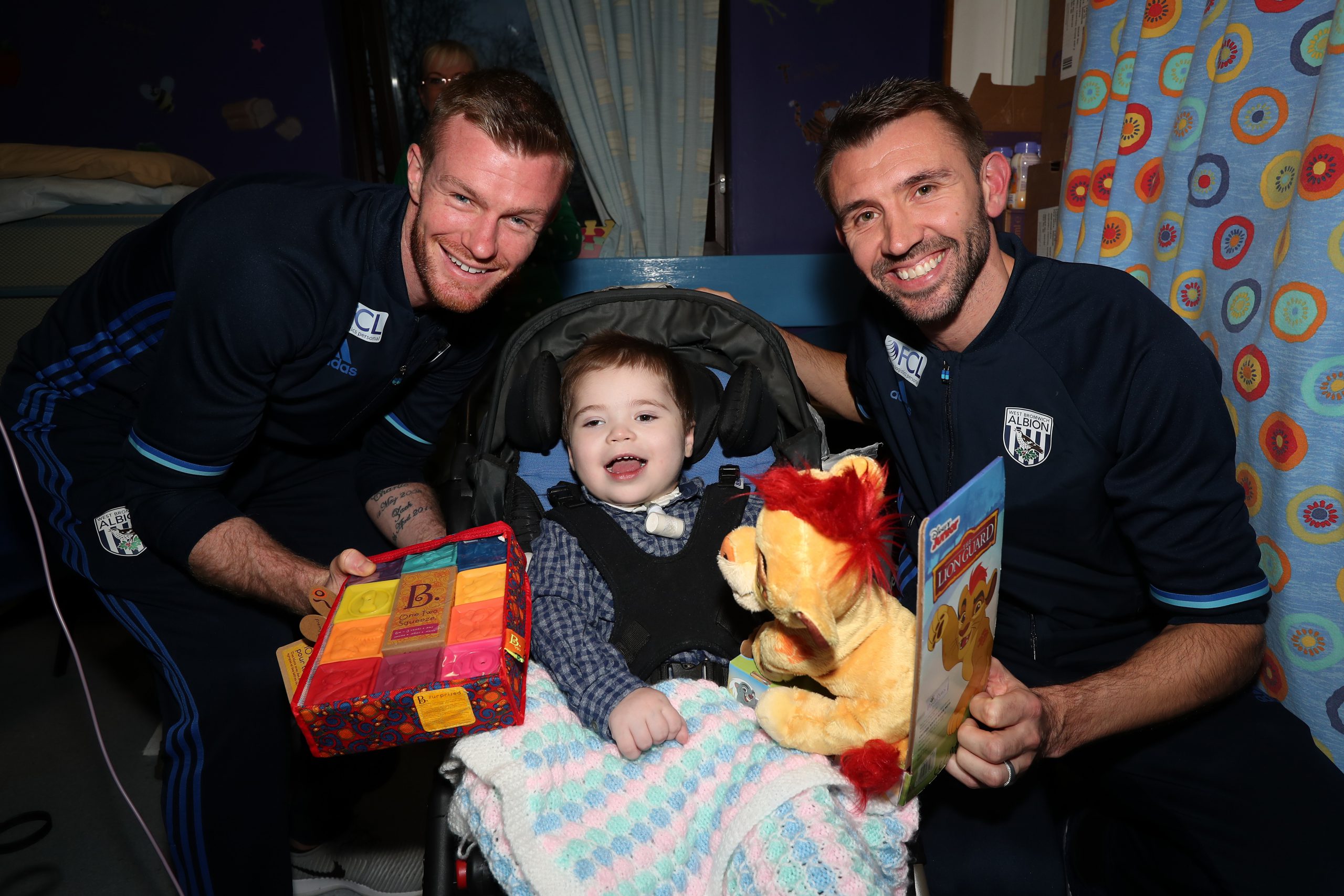 Chris Brunt of West Bromwich Albion and Gareth McAuley of West Bromwich Albion with Loki Hudson aged 3 at Sandwell Hospital where West Bromwich Albion players handed out Christmas presents  to sick children