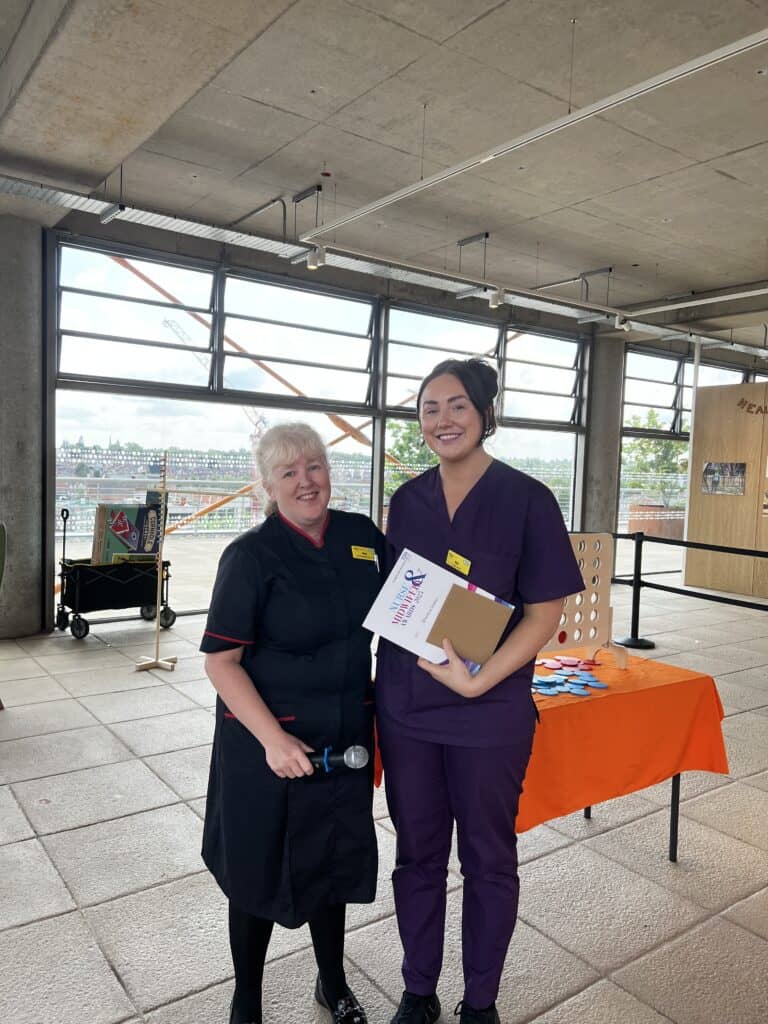 Lady smiling next to a lady who is holding a certificate