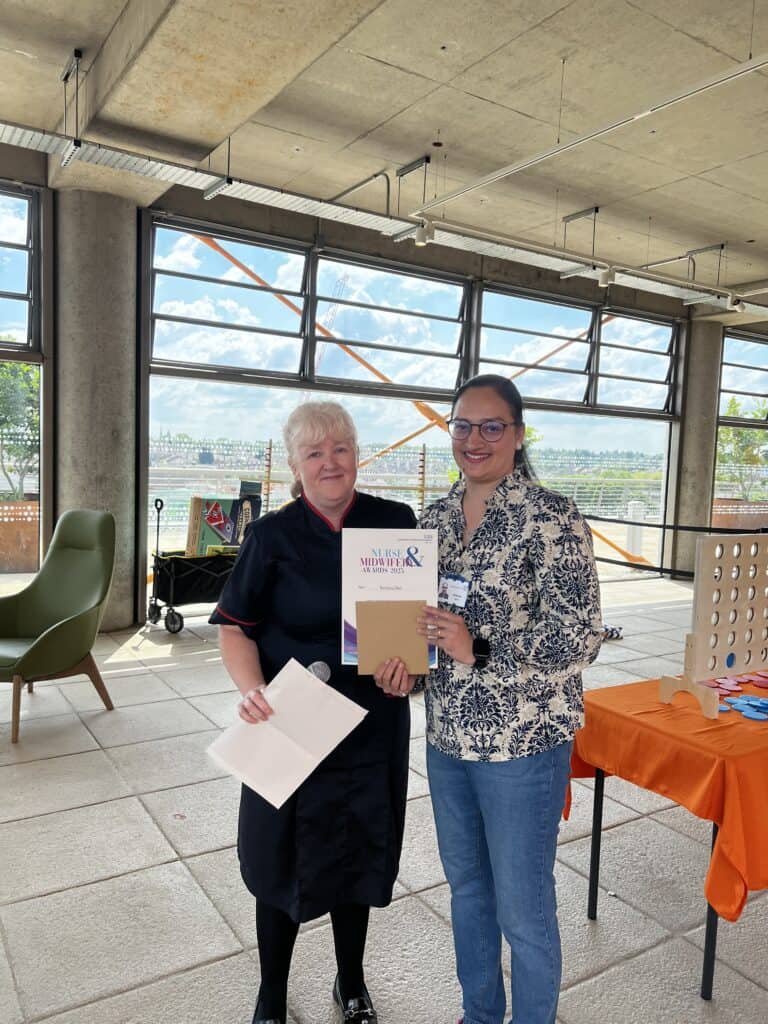 Lady smiling next to a lady who is holding a certificate