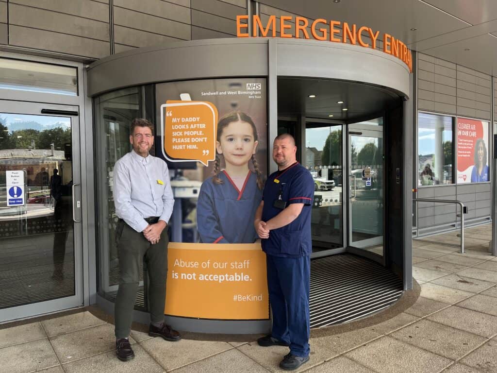 Two men stood outside the doors of an emergency department.