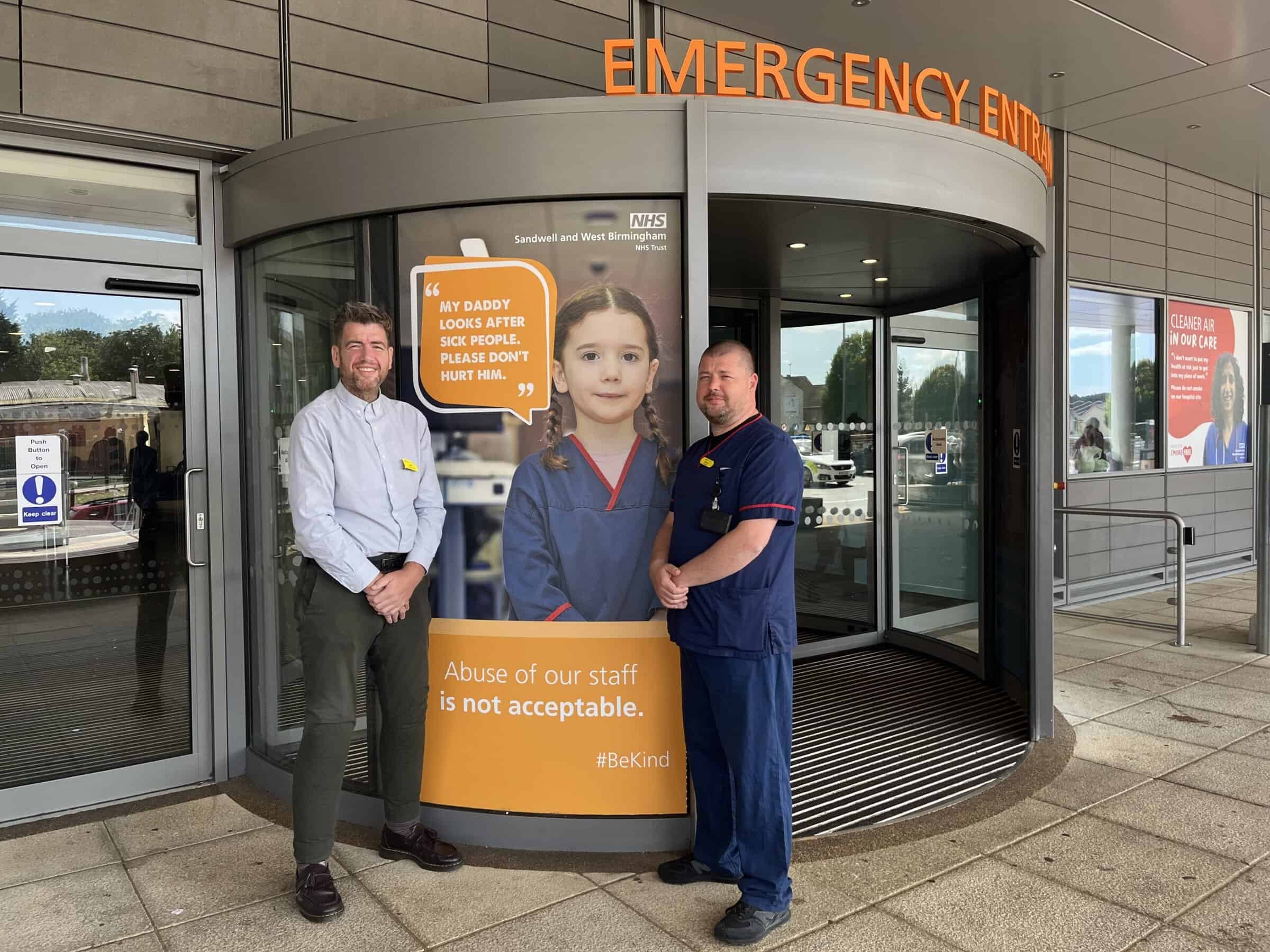 Two men stood outside the doors of an emergency department.