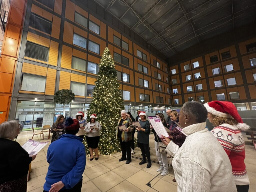 Carol singers in front of a Christmas Tree
