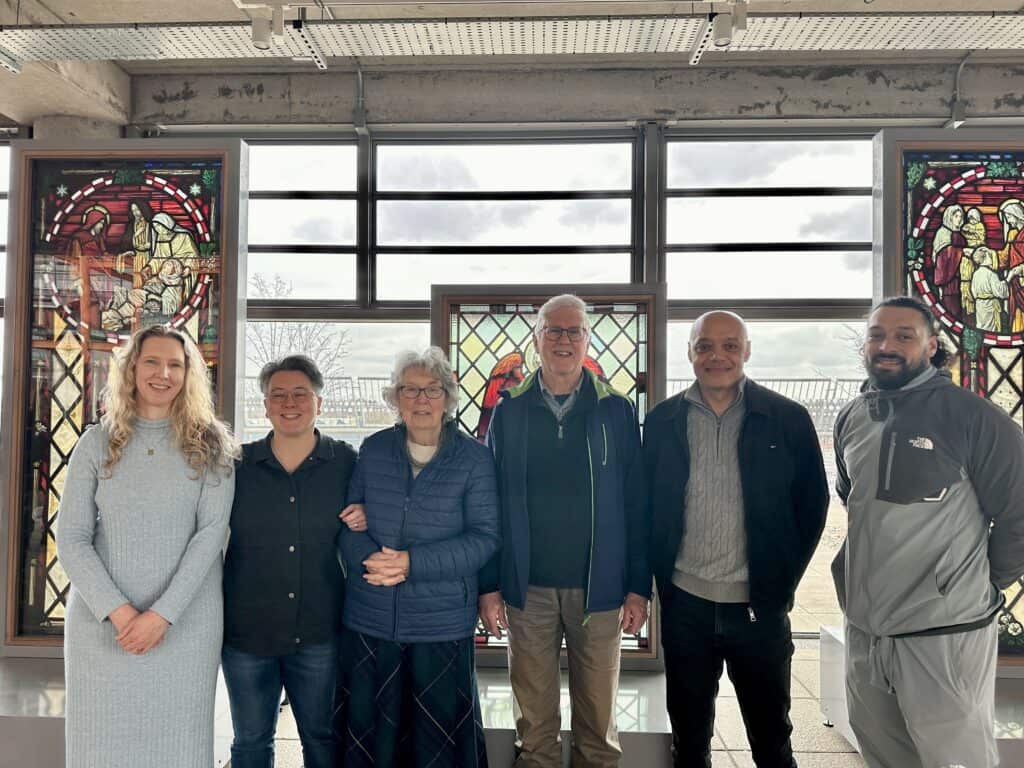 A photo of a group of people in front of stained glass windows displayed in a hospital gallery.