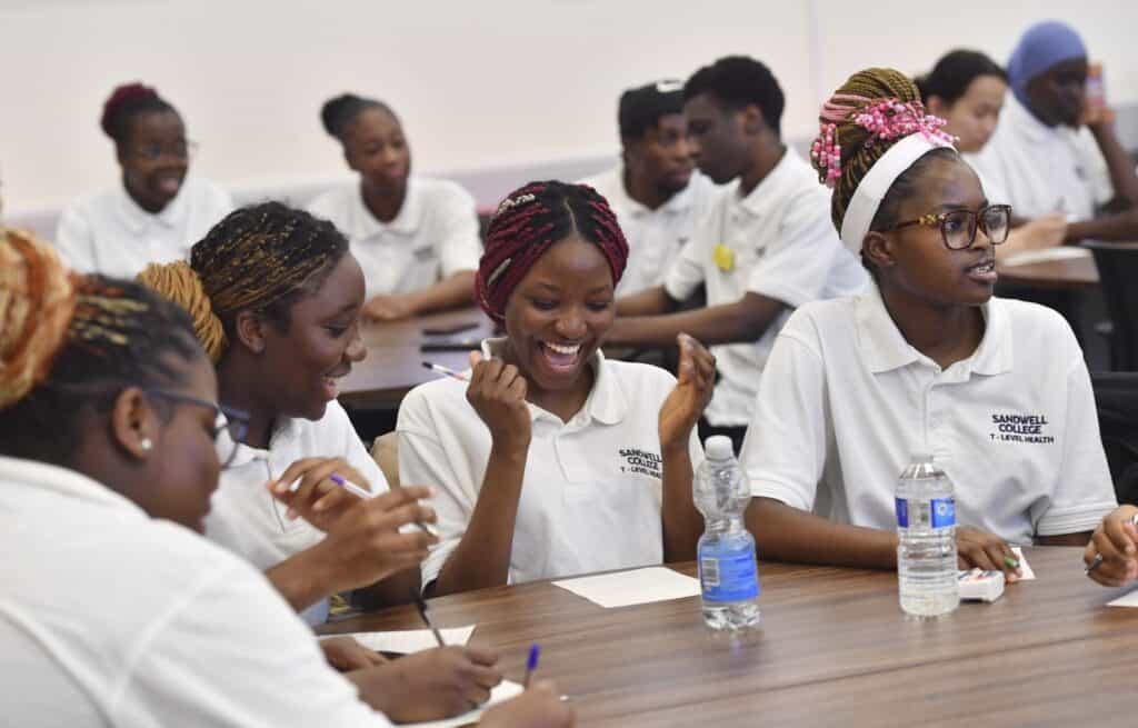 Group of students sat at a table laughing and enjoying their day