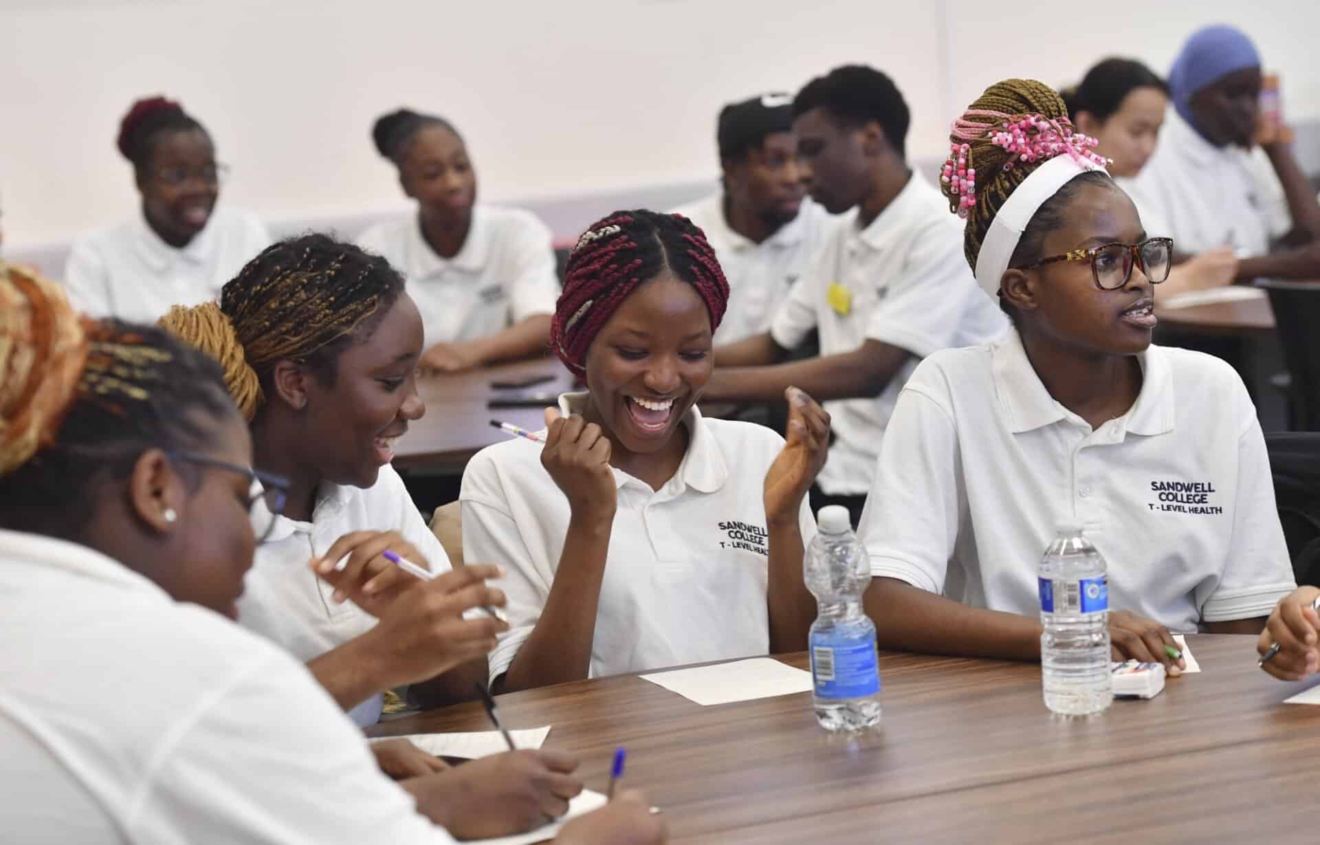 Group of students sat at a table laughing and enjoying their day